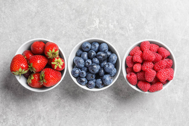 Bowls with raspberries, strawberries and blueberries on table, top view - Foto, Bild