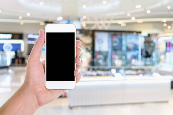 Un homme tenant à la main un téléphone intelligent avec écran d'espace de copie vierge dans un grand magasin ou un centre commercial
 - Photo, image
