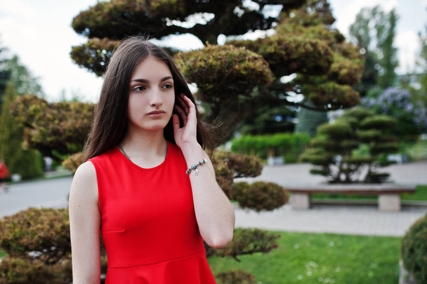 Teenage girl in red dress posed outdoor at sunny day. - Zdjęcie, obraz
