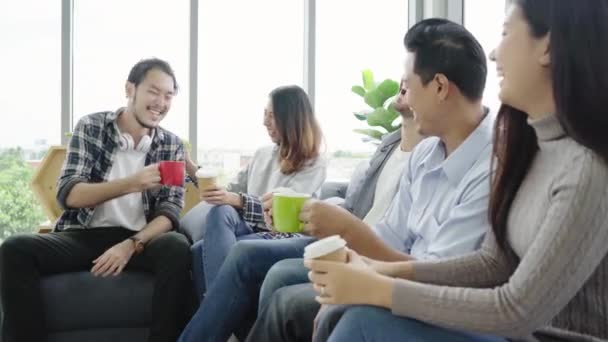 Diversity of young people group team  holding coffee cups and discussing something with smile while sitting on the couch at office. Coffee break time at creative office.  - Footage, Video