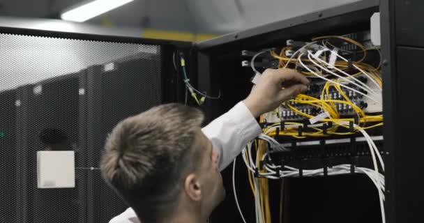 Ingeniero masculino del servidor camina a través del centro de datos de trabajo lleno de servidores en rack
 - Metraje, vídeo