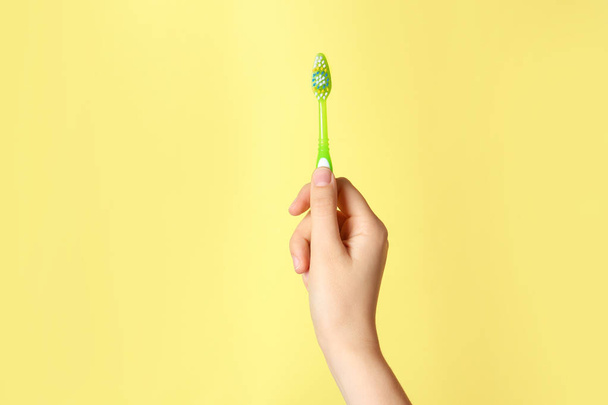 Woman holding manual toothbrush against color background - Photo, image