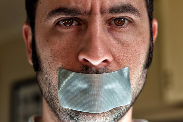 Close up portrait of a man with duct tape over his mouth - Foto, imagen