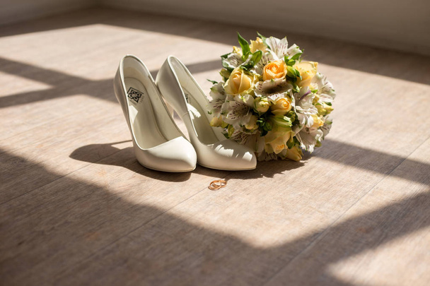 Свадебный букет с туфлями и кольцами. Обручальные кольца и обувь на фоне букета цветов
. - Фото, изображение