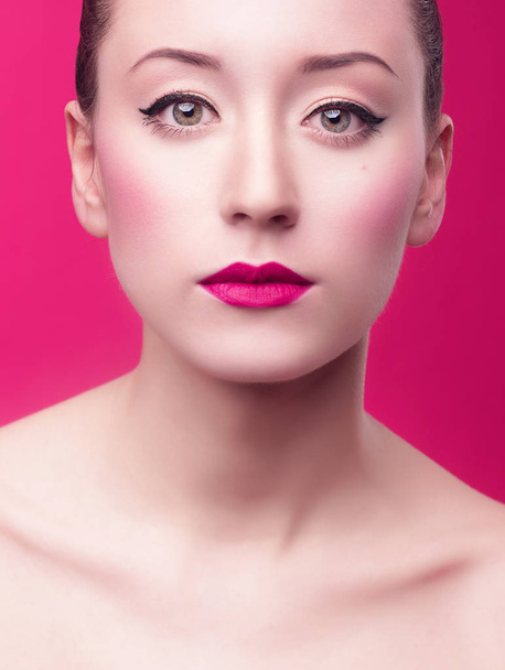 portret Piękna Azjatka brunetka kobieta z doskonałą czystość skóry, różowe usta i jasny makijaż z czarny eyeliner na różowym tle - Zdjęcie, obraz
