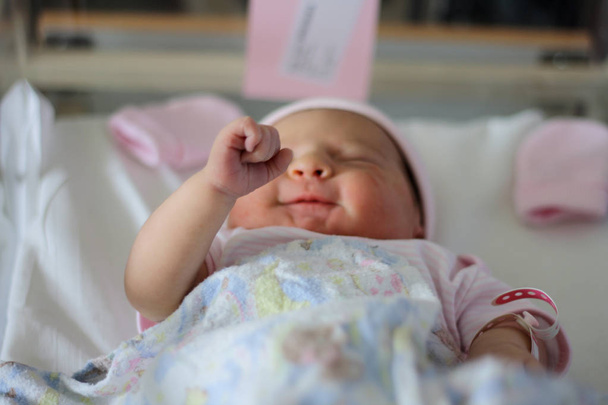Nouveau-né bébé fille soulève son poing tout en étant couché et sentant
 - Photo, image