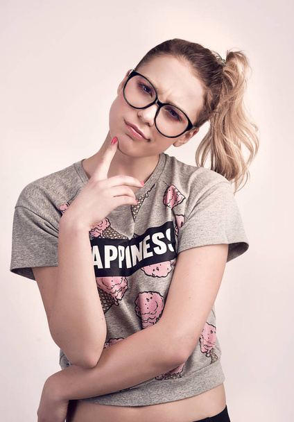 portrait of young thoughtful girl wearing hipster glasses and funny t-shirt  - Foto, Imagen
