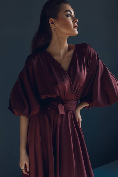 Young elegant girl in burgundy dress. Beauty portrait - Фото, изображение