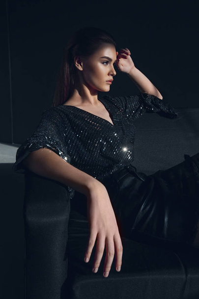 Young elegant girl in black shiny suit in sequins. Beauty portrait - Photo, image