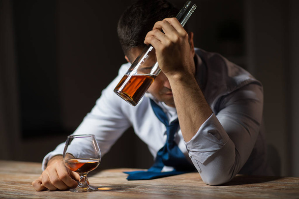 drunk man drinking alcohol at table at night - Фото, изображение