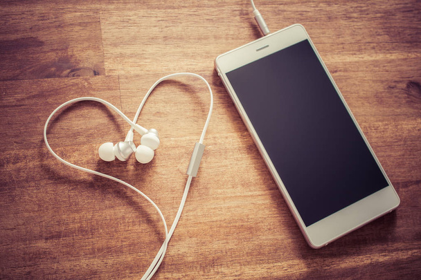 Láska poslech hudby koncept bílý mobilní telefon a srdcem ve tvaru sluchátek s mikrofonem - Fotografie, Obrázek