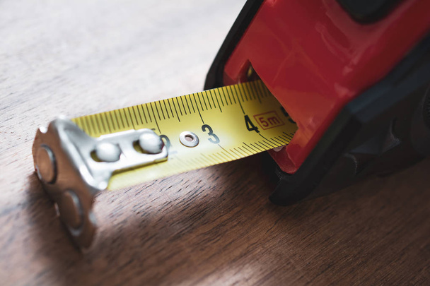 Um close-up de uma fita de medição sólida com escala puxada para fora de pé em uma mesa
 - Foto, Imagem