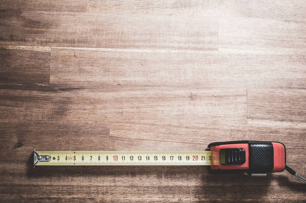 A Solid Measuring Tape With Pulled Out Scale Lying At The Bottom Of A Wooden Table, Top Down View - Foto, imagen