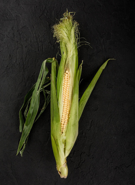 Friss kukorica a cob a sötét kő asztal. Élelmiszerek fogalmát, felülnézet - Fotó, kép