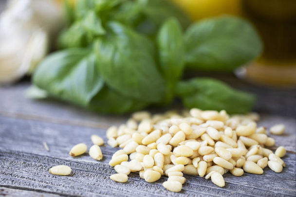 Pine nuts with basil and other pesto ingredients in the background. - Fotoğraf, Görsel