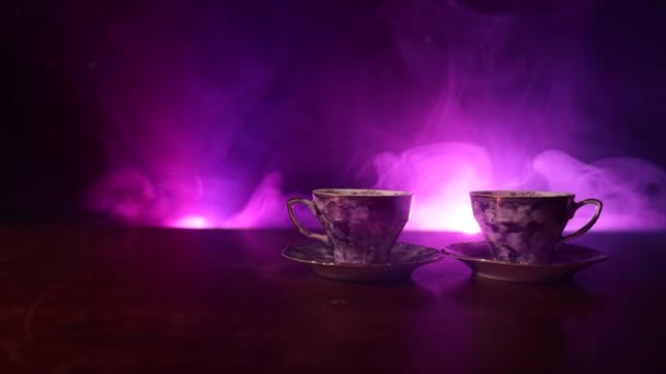 Koffie of thee ceremonie conceptuele thema. Oude vintage keramische thee of koffiepot met cups kruik en suiker cup op donker getinte achtergrond met licht en rook. Lege ruimte voor tekst. Schuifregelaar schot - Video