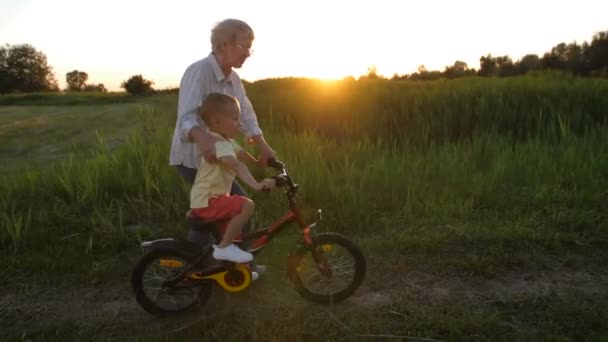 Niño pequeño montar en bicicleta con las abuelas ayuda
 - Metraje, vídeo