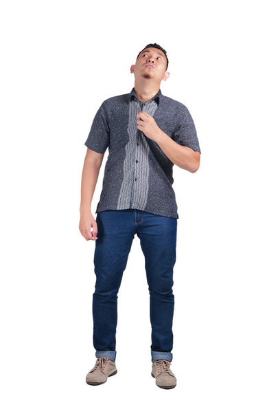 young Asian manwearing blue jeans and batik shirt, feeling heat gesture. Isolated on white, Full body portrait - Foto, afbeelding