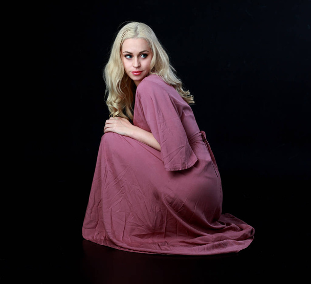 Pełna długość Portret blondynka dziewczynka długo fioletowy sukience. w pozycji siedzącej pozie. czarny studio tło. - Zdjęcie, obraz