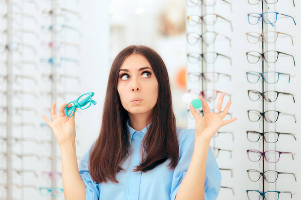 Woman Choosing Between Glasses and Contact Lenses in Optics Shop - Photo, image