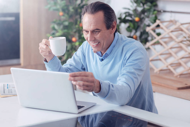 Delighted positive man adjusting laptop screen - Photo, image