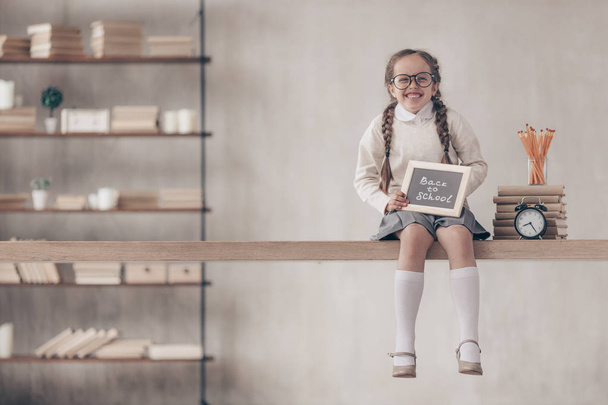Ευτυχισμένος μικρή μαθήτρια με μια πλάκα στο στούντιο - Φωτογραφία, εικόνα