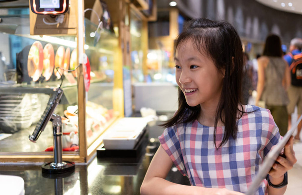 Asian cute girl ordering from menu at food court in mall - Photo, Image