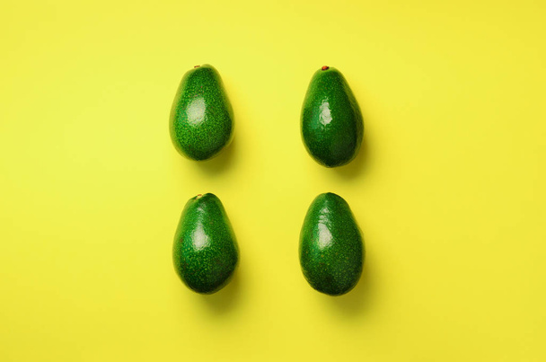 Green avocado pattern on yellow background. Top view. Pop art design, creative summer food concept. Organic avocadoes in minimal flat lay style. - Zdjęcie, obraz