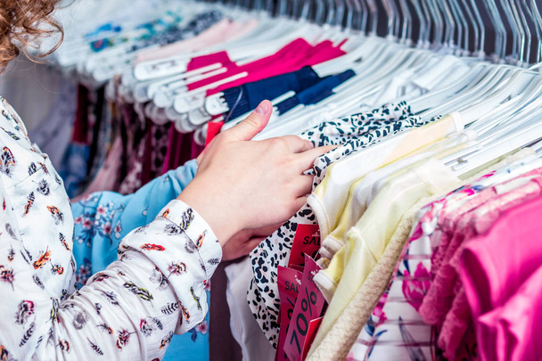 Дівчина в модному магазині вибирає блузку на літо
 - Фото, зображення