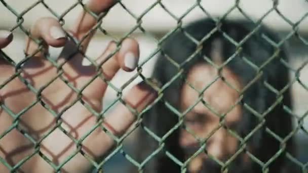 Blows on mesh fence with womens hands. Angry girl beats hands on a grid fence - Felvétel, videó