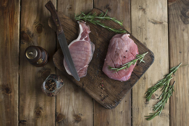 raw pork meat on a wooden board and knife, spices and rosemary. - 写真・画像