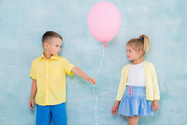 Boy child gives a balloon to a girl. Signs of attention, sympathy and courtship. - Фото, зображення