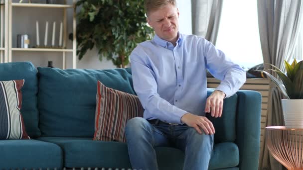 Мужчина средних лет с болью в коленях сидит на диване
 - Кадры, видео