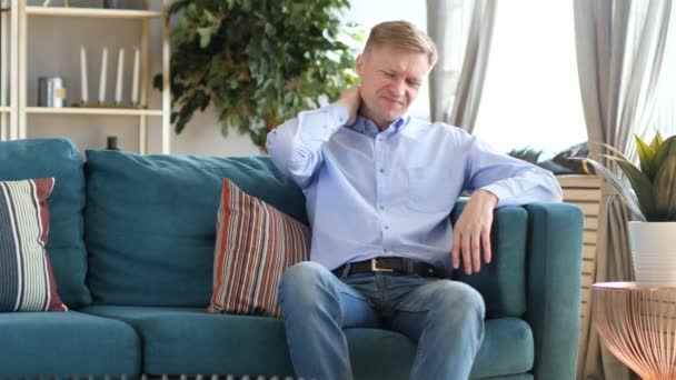 Hombre de mediana edad con dolor de hombro sentado en el sofá
 - Imágenes, Vídeo