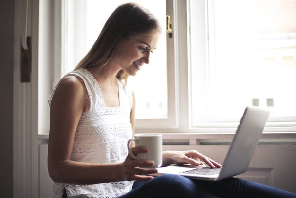 Young woman with a laptop and a cup of drink. - Photo, image