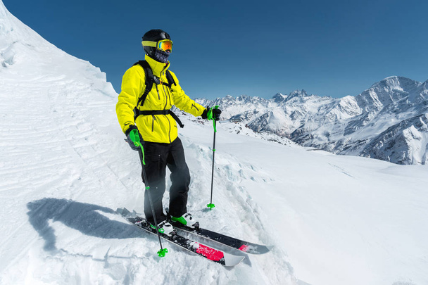 A freerider skier in complete outfit stands on a glacier in the North Caucasus against the background of the Caucasian snow-capped mountains - Photo, Image