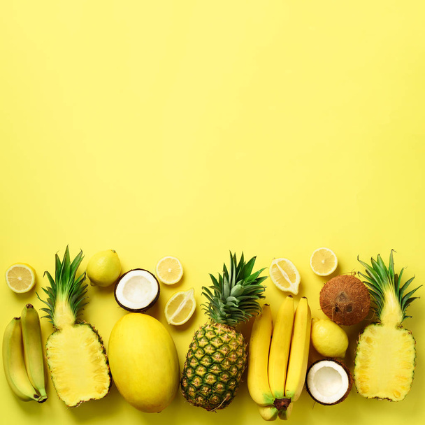 Fresh organic yellow fruits over sunny background. Monochrome concept with banana, coconut, pineapple, lemon, melon. Top view. Copy space. Pop art design, creative summer design. Vegan food. Flat lay - Photo, image