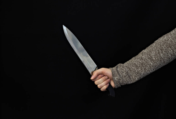 Hand of a girl with a knife on a black background, close-up - Foto, Imagen