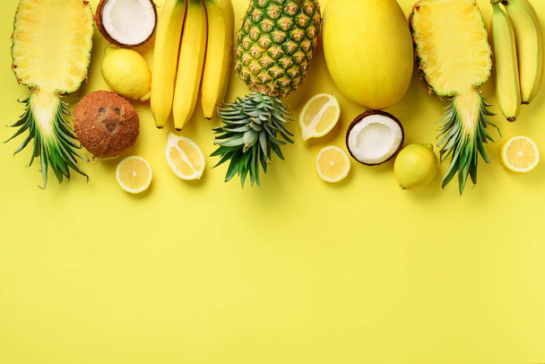 Fresh organic yellow fruits over sunny background. Monochrome concept with banana, coconut, pineapple, lemon, melon. Top view. Copy space. Pop art design, creative summer design. Vegan food. Flat lay - 写真・画像