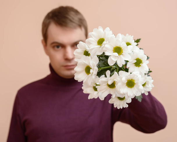 Genç adam elinde beyaz çiçekli. - Fotoğraf, Görsel