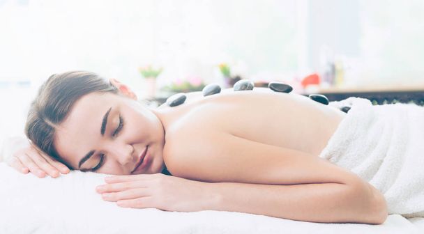 Frau bekommt Hot Stone Massage Behandlung durch professionelle Kosmetikerin Therapeutin im Wellness-Salon. Luxuriöses Wellness-, Rückenstress- und Verjüngungskonzept. - Foto, Bild