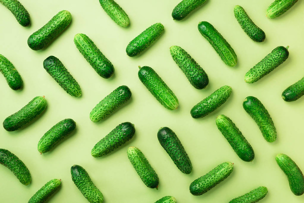 Creative pattern of fresh cucumbers on green background. Top view. Copy space. Minimal design. Vegetarian, vegan, organic food and alkaline meal concept - Foto, immagini