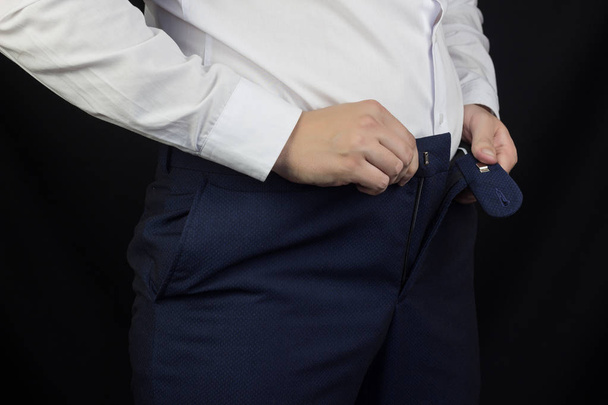 A fat man in a white shirt and trousers can not fasten his pants, overweight, close-ups - Foto, Bild