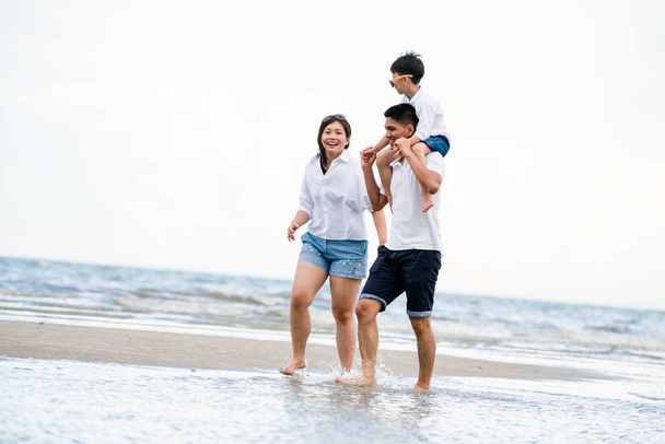 Felice famiglia di padre, madre e figlio va in vacanza su una spiaggia di sabbia tropicale in estate
. - Foto, immagini