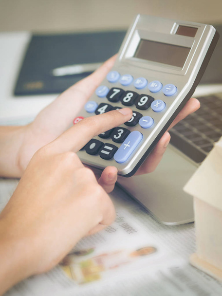 Женщина-бухгалтер или банковский работник использует калькулятор в офисе для учета прибыли и убытков
. - Фото, изображение