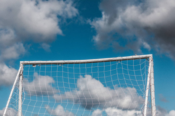 Nahaufnahme eines Fußballtorpfostens mit wolkenverhangenem blauem Himmel im Hintergrund - Foto, Bild