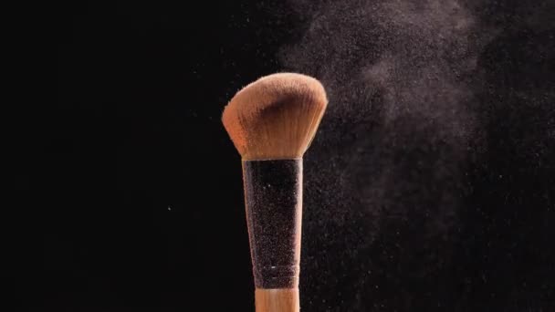 Make-up και ομορφιά έννοια. Βούρτσα με ροζ σκόνη έκρηξη σε μαύρο φόντο - Πλάνα, βίντεο