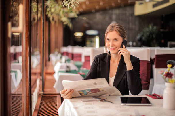 Mujer rubia en un restaurante hablando en su smartphone
. - Foto, Imagen