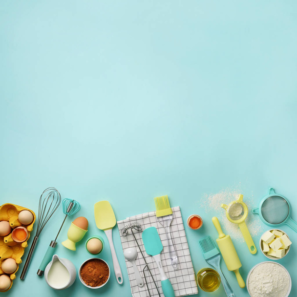Square crop. Baking ingredients - butter, sugar, flour, eggs, oil, spoon, rolling pin, brush, whisk, towel over blue background. Bakery food frame, cooking concept. Top view, copy space. Flat lay - Φωτογραφία, εικόνα
