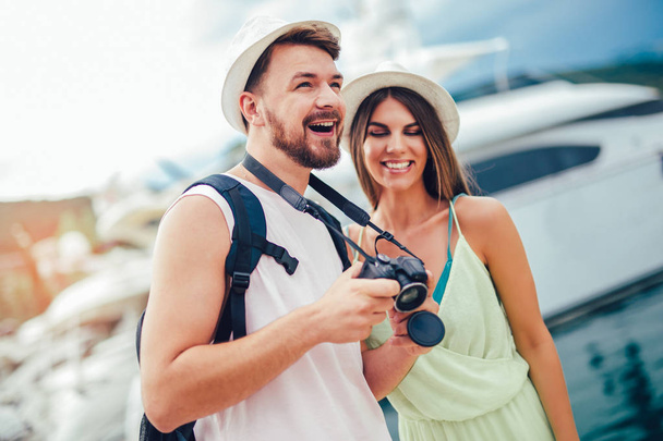 Pareja de viajeros caminando en complejo marítimo cerca de yates. Hombre y mujer turistas felices
.  - Foto, imagen